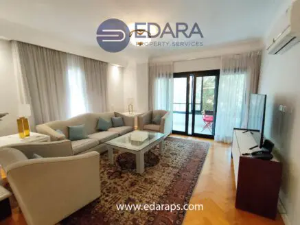 Contemporary living room with a sofa, decorative pillows, and a television in a bright space.