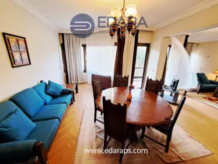 Living room featuring a round dining table and a blue sofa with wooden chairs in a well-lit space.