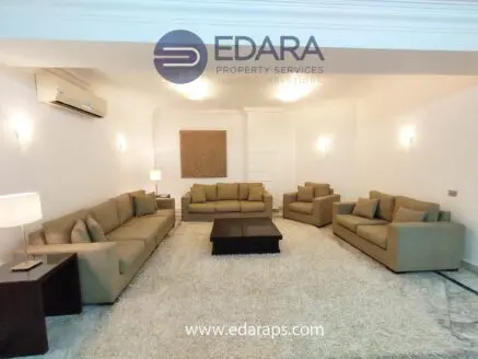 Spacious living room featuring beige sofas, a coffee table, and a light-colored rug.