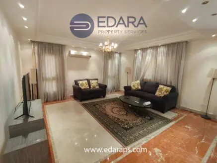 Modern living room featuring a dark sofa with decorative cushions, a television, and a coffee table on a marble floor.