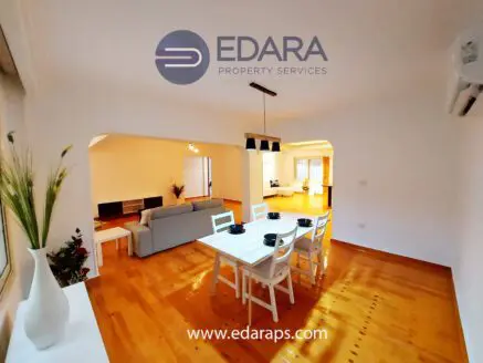 Dining area featuring a wooden table set with chairs and a view of a living space in the background.