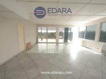Interior view of a spacious room with large windows allowing natural light to enter, featuring marble flooring.