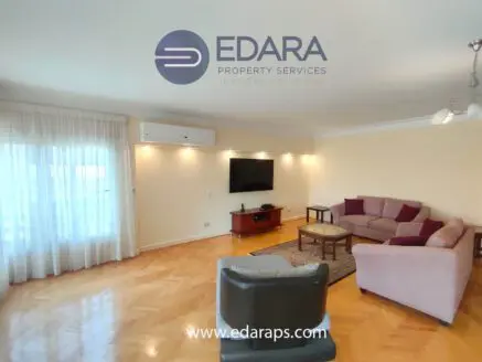 Spacious living room featuring a sofa, coffee table, and wall-mounted television in a neutral color scheme.