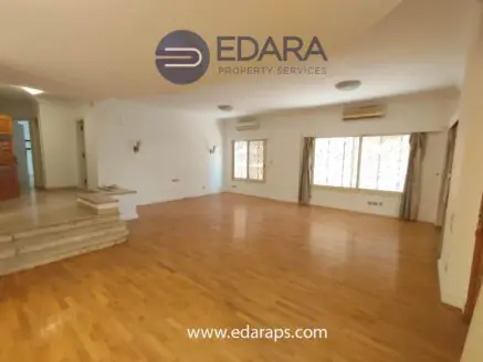 Bright and spacious living room featuring wooden flooring and large windows for natural light.