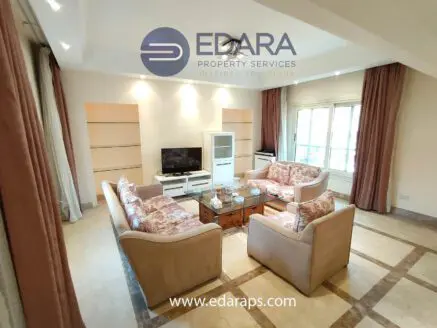 Living room featuring floral patterned sofas, a coffee table, and a television unit against a light-colored wall.