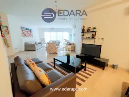 Contemporary living room with a sofa, coffee table, and television in a well-lit space.
