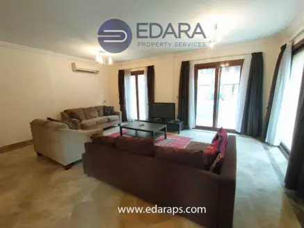 Spacious living room featuring a sofa, coffee table, and large windows with curtains.