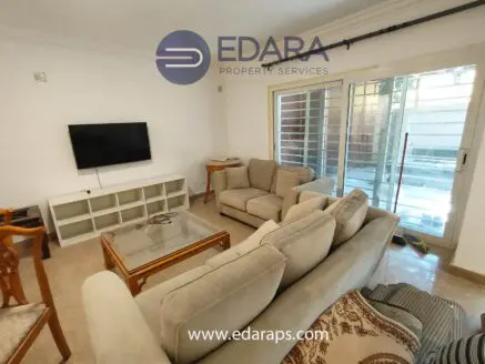 Living room featuring a beige sofa set, a glass coffee table, and a television mounted on the wall.