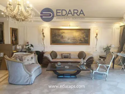 Luxurious living room featuring a beige sofa, ornate chairs, and decorative artwork on the walls.
