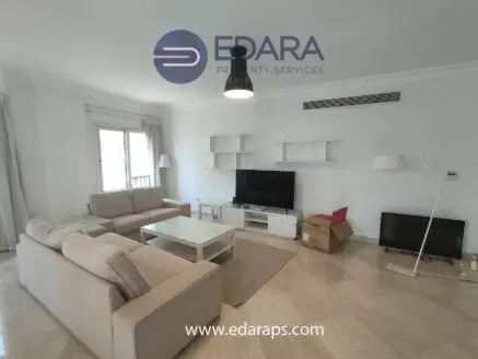 Modern living room featuring a beige sofa, television, and minimalist furniture design.