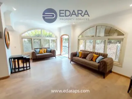 Living room featuring two tufted sofas with yellow cushions and large arched windows allowing natural light.