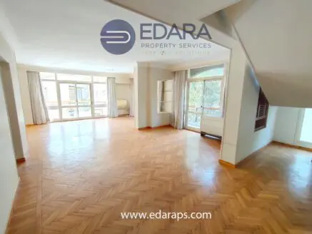 Bright and spacious living room featuring wooden herringbone flooring and large windows for natural light.