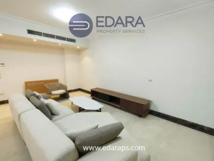 Modern living room featuring a light-colored sofa, coffee table, and TV unit against a neutral wall.