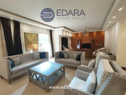 Contemporary living room with light-colored sofas and a wooden entertainment unit.
