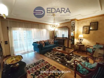 Living room featuring a blue sofa, decorative pillows, wooden furniture, and a patterned rug.
