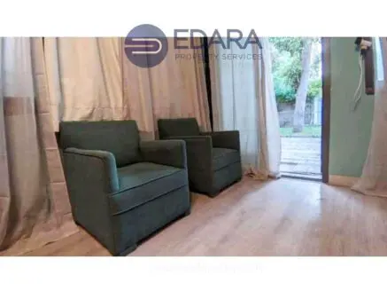 Two green armchairs positioned in a room with light-colored flooring and curtains.