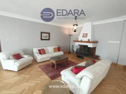 Spacious living room featuring white sofas, a wooden coffee table, and a fireplace with a chimney.