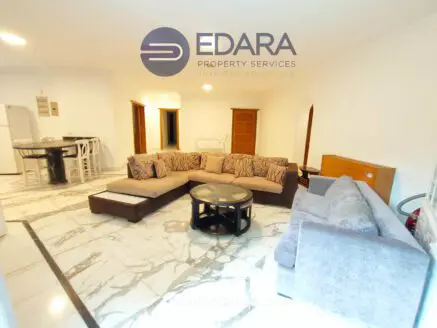 Living room featuring a large sectional sofa and a round coffee table on a marble floor.