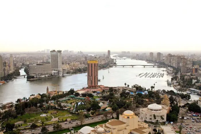 Aerial view of Cairo showcasing the Nile River and city skyline with buildings and greenery.