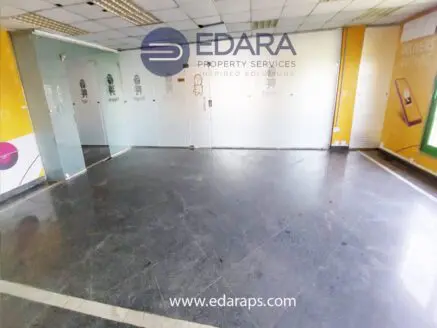 Interior view of an empty commercial space featuring glass doors and tiled flooring.