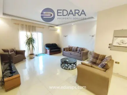 Spacious living room with two sofas, a coffee table, and a large window allowing natural light.