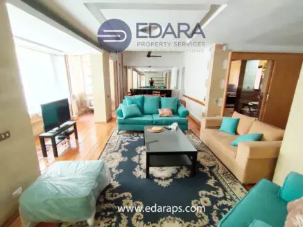 Living room featuring turquoise sofas, a coffee table, and a television in a well-lit space.
