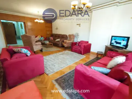 Living room featuring red sofas, a television, and a wooden coffee table in a residential setting.