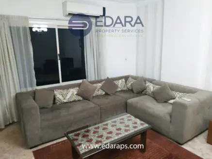Gray sectional sofa with decorative cushions and a wooden coffee table in a living room setting.