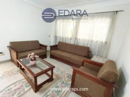 Living room with two brown sofas, a coffee table, and a floral arrangement on the table.