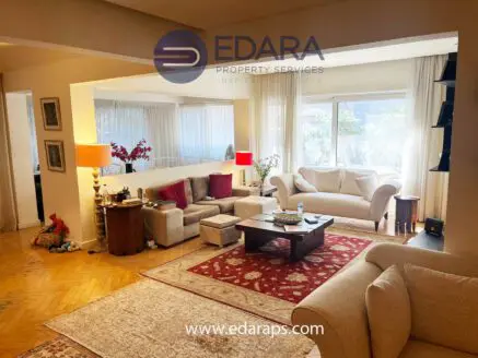 Spacious living room featuring beige sofas, a wooden coffee table, and a decorative rug.