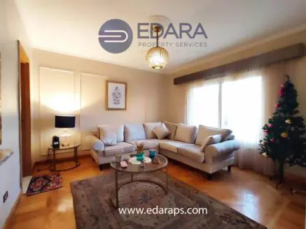 Living room featuring a light-colored sofa, decorative rug, and a Christmas tree in the corner.