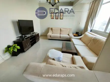 Living room featuring a beige sofa set, a television on a stand, and a glass coffee table.