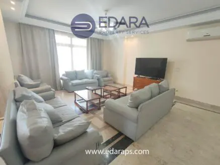 Living room featuring light gray sofas, a wooden coffee table, and a television on a stand.