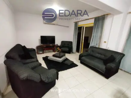 Living room featuring black upholstered sofas arranged around a central coffee table on a dark rug.