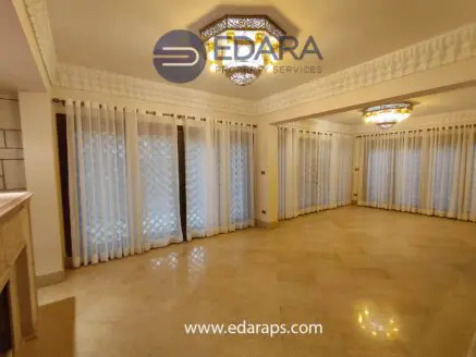 Bright living room featuring decorative ceiling lights and large windows with sheer curtains.