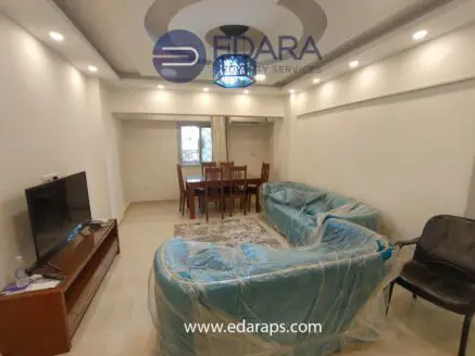 Living room featuring a sofa and dining table, both covered in protective plastic wrap.