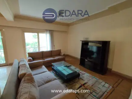 Living room featuring a beige sofa set and a glass coffee table on a patterned rug.