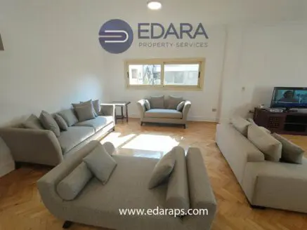 Contemporary living room with light gray sofas and a large window allowing natural light.
