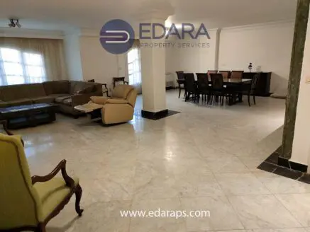 Interior view of a spacious living room featuring a sofa set and dining table in a modern design.