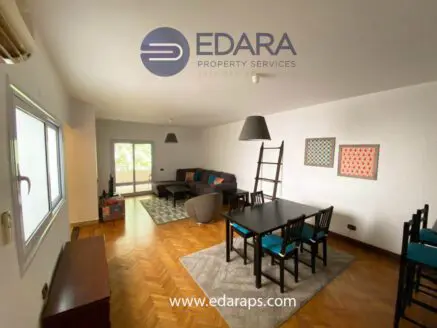 Interior view of a living room featuring a sofa, dining table, and decorative wall art.