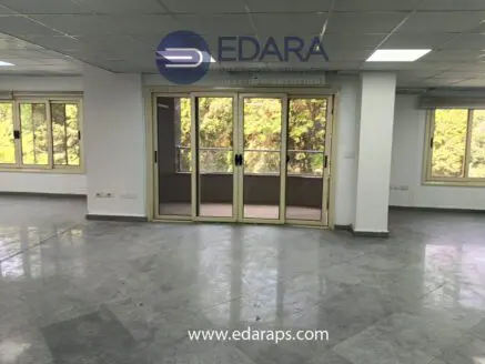 Spacious interior room with large windows allowing natural light and a tiled floor.