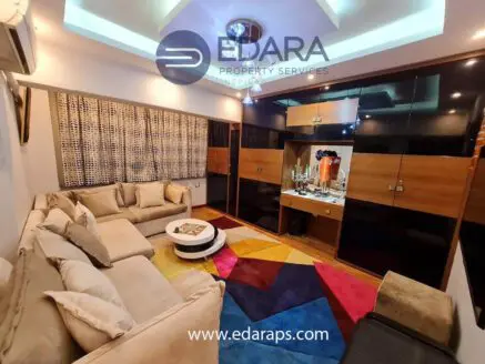 Contemporary living room with beige sofa, colorful rug, and stylish decor elements.