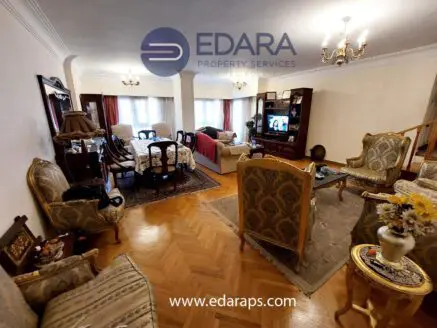 Spacious living room featuring traditional furniture, a television, and decorative elements in a well-lit space.