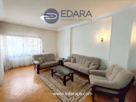 Living room featuring beige sofas, a coffee table, and a decorative rug on a wooden floor.
