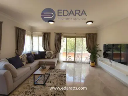 Spacious living room featuring a gray sofa, decorative pillows, and a television mounted on the wall.