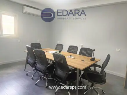 Conference room featuring a wooden table surrounded by black ergonomic chairs and a projector setup.