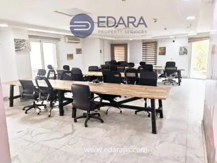 Contemporary office space featuring multiple desks and ergonomic chairs arranged in a collaborative layout.