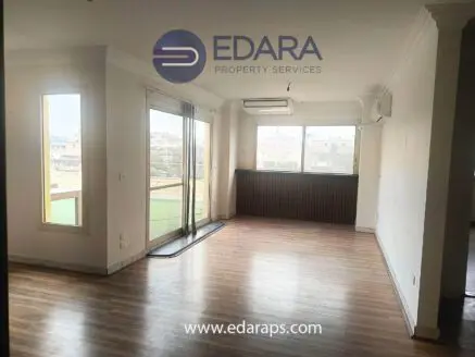 Empty residential apartment interior with large windows and wooden flooring.