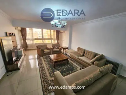 Spacious living room featuring beige sofas, a wooden coffee table, and a decorative rug.