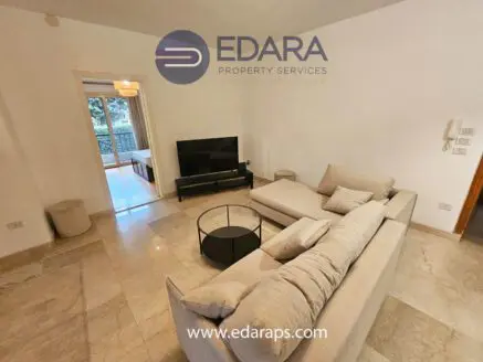 Contemporary living room featuring a light-colored sofa and a round coffee table on a marble floor.